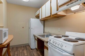 A compact kitchen with a refrigerator, microwave, sink, and stove. - Extended Stay America Suites Evansville East (Evansville)