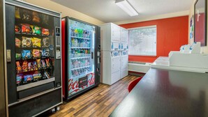 Una kitchenette equipada con refrigerador, máquina expendedora y microondas.