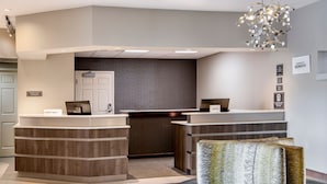 A hotel reception area with a modern design, featuring a reception desk, a seating area with a patterned cushion, and a chandelier. - Residence Inn by Marriott Cincinnati Airport Erlanger (Erlanger)