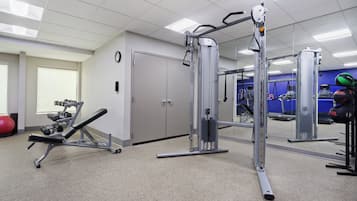 A gym with exercise equipment, a clock, and a door.