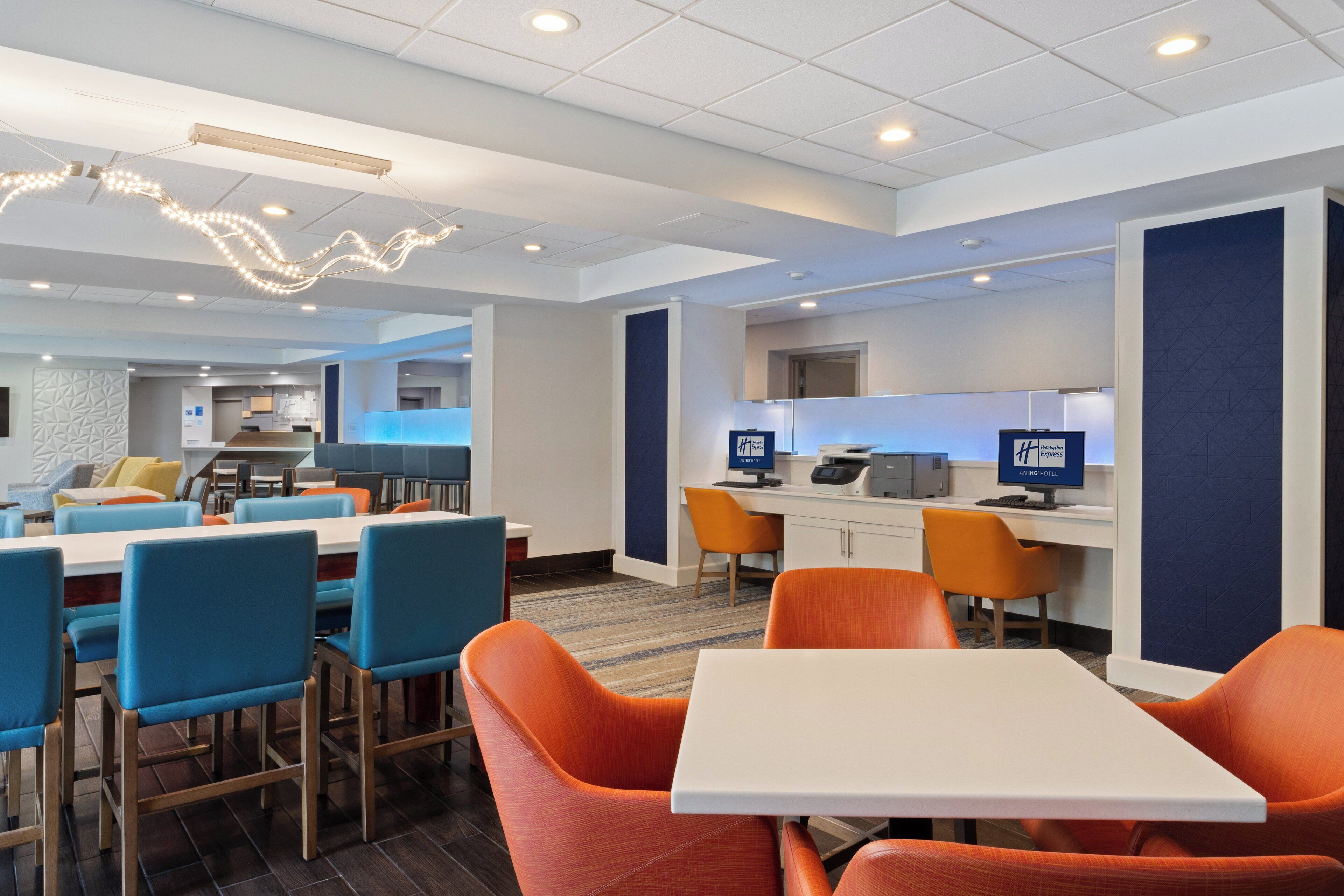A modern hotel lobby with a seating area, a reception desk, and a kitchenette.