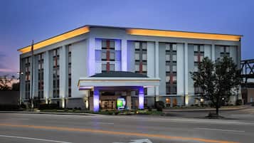 Un hotel moderno con una entrada destacada, ventanas amplias y una fachada bien iluminada.