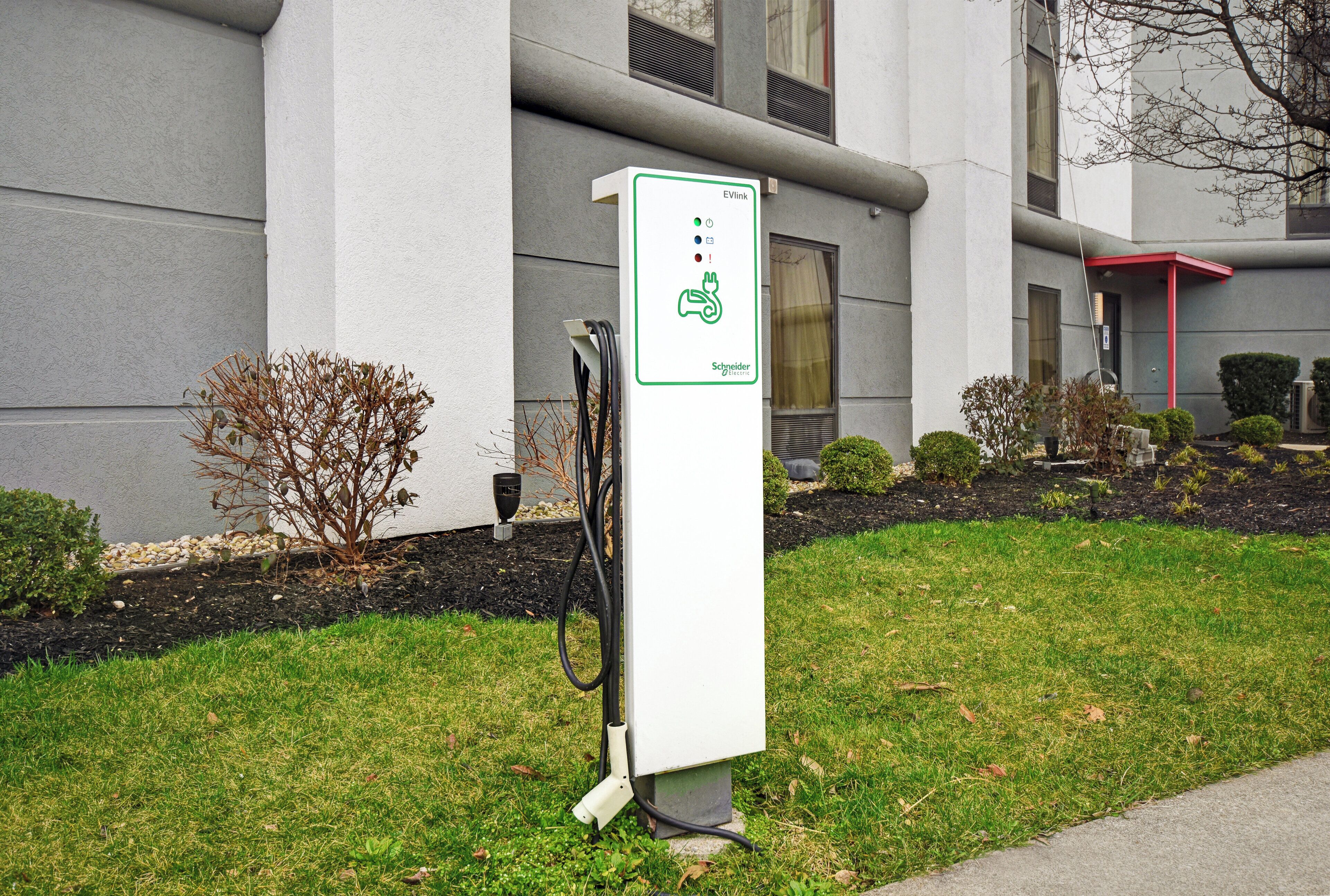 An EVlink charging station in a landscaped area with a building in the background.