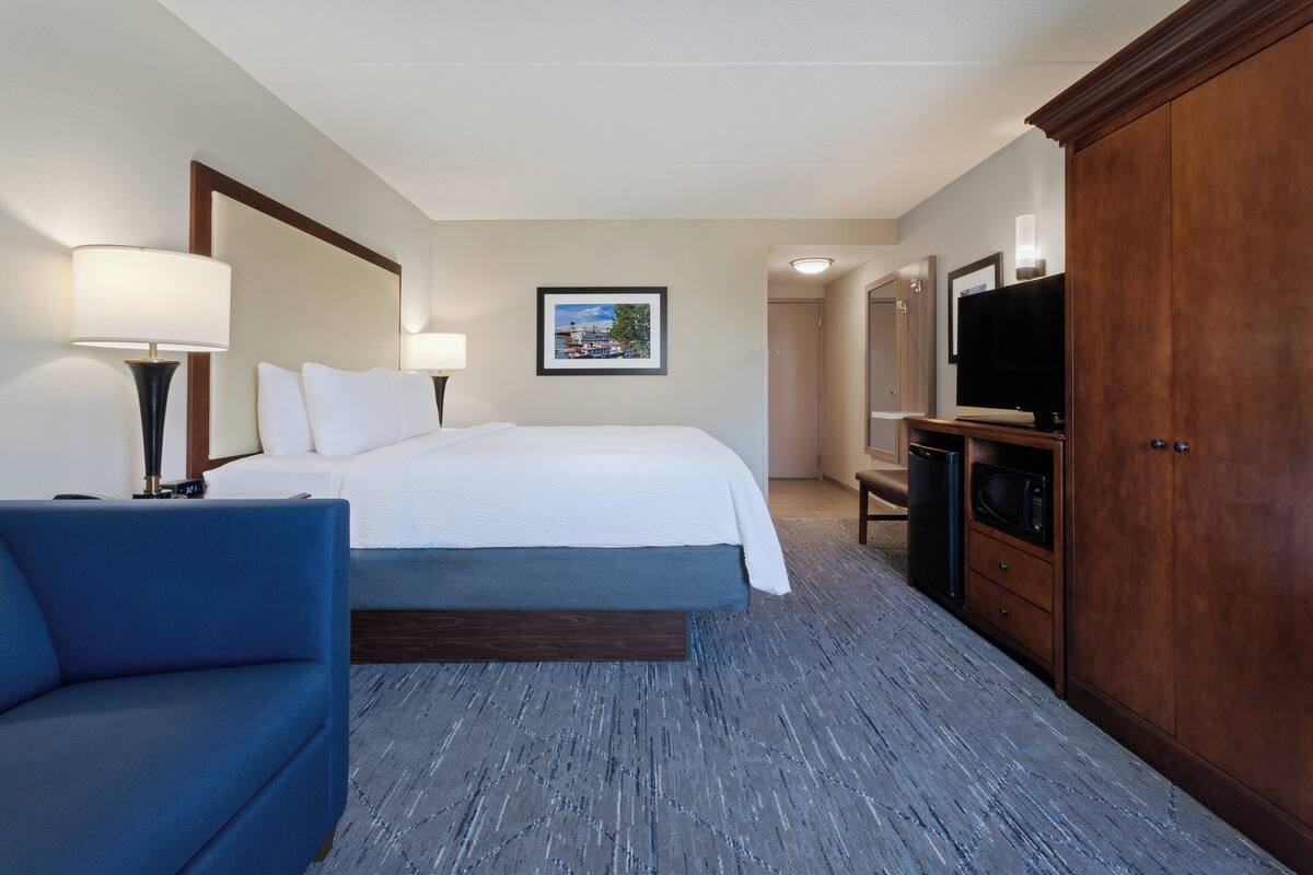 A hotel room with a bed, a desk, a television, and a wardrobe.
