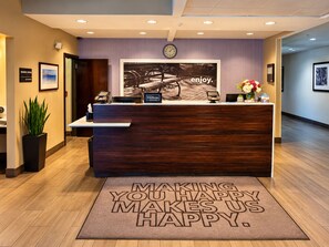 A hotel reception desk with a clock, a framed picture, and a welcome mat. - Hampton Inn Elizabethtown KY (Elizabethtown)
