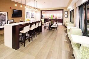 A modern hotel dining area with a long bar, multiple dining tables, and chairs.