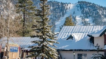 Eine Berghütte mit schneebedecktem Dach, ein Schild für das Postmark Hotel & Suites und im Hintergrund schneebedeckte Bäume und Berge.
