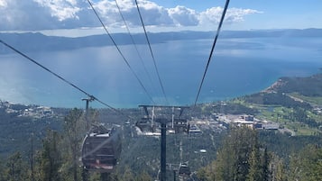 Sistema de teleférico con vista a un lago y montañas al fondo.