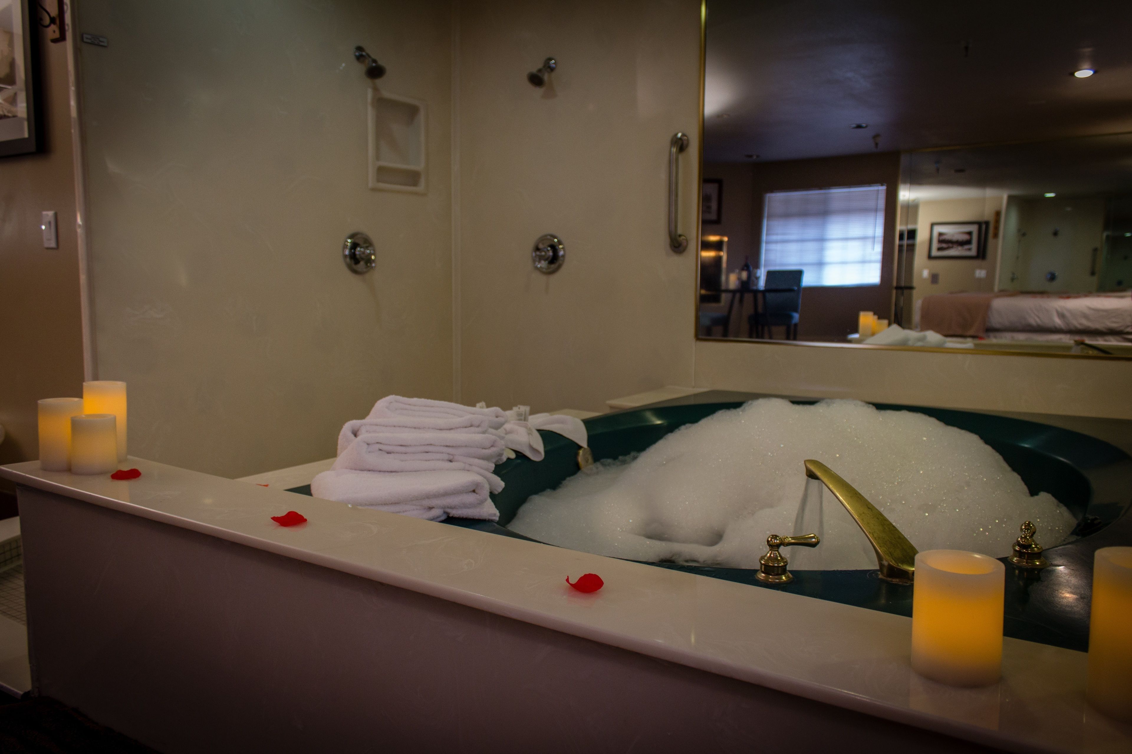 Un baño con una bañera llena de burbujas, un lavamanos con velas y toallas ordenadas.