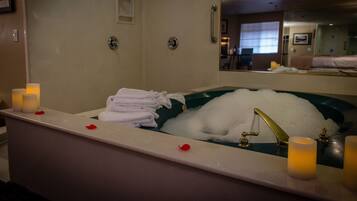 Un baño con una bañera llena de burbujas, un lavamanos con velas y toallas ordenadas.
