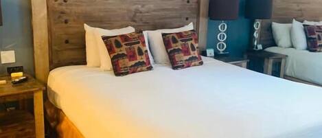 Une chambre d’hôtel avec un grand lit, une tête de lit en bois et un mur sur lequel le mot « LAC » est écrit en lettres.