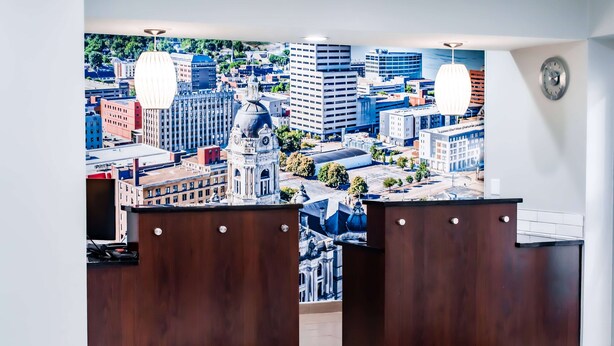 Una zona de recepción con un mural de la ciudad, mostradores de madera y luces colgantes.