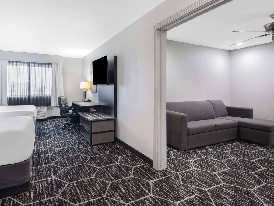 A hotel room with a bed, a desk with a computer, a sofa, and a TV.