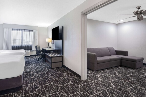 A hotel room with a bed, a desk with a computer, a sofa, and a TV. - La Quinta Inn & Suites by Wyndham Evansville (Evansville)