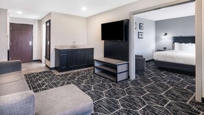 Una habitación de hotel moderna con sofá, televisión, cama y baño.