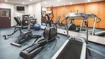 A gym with various exercise equipment including treadmills, elliptical machines, and free weights.