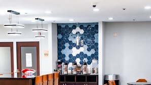 Un área de comedor moderna con suelo de mármol, un sofá largo color naranja y una alfombra estampada.