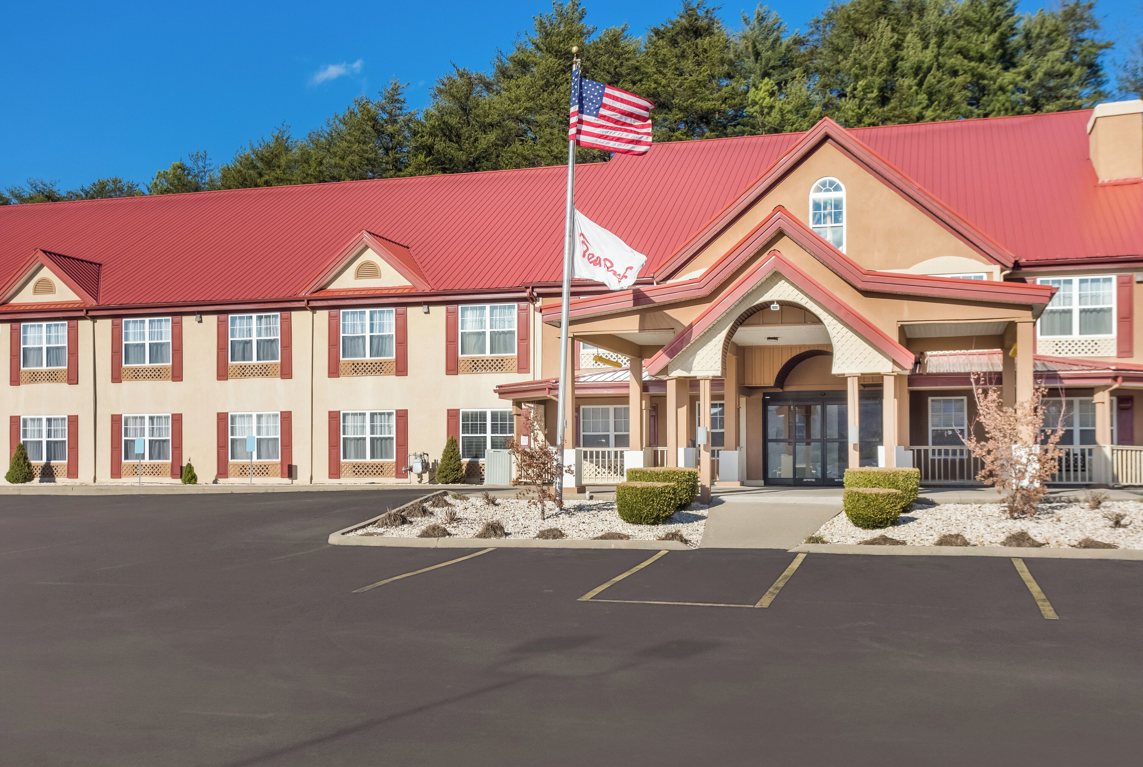 A hotel with a red roof, a flag, and a sign that reads 'Resort.'
