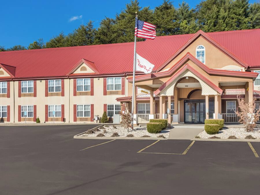 A hotel with a red roof, a flag, and a sign that reads 'Resort.'