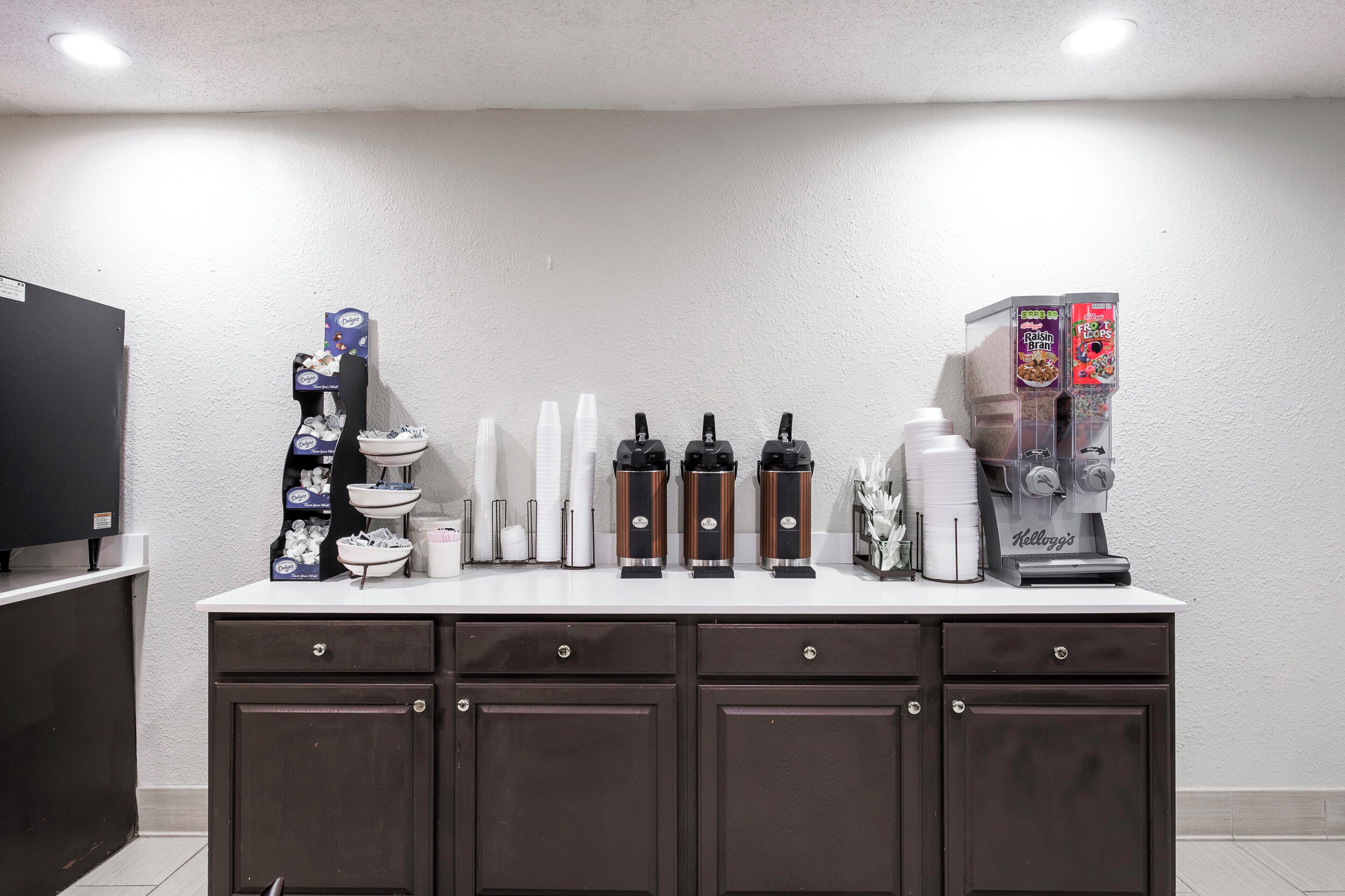 Una kitchenette equipada con cafetera, dispensador de té y refrigerador.