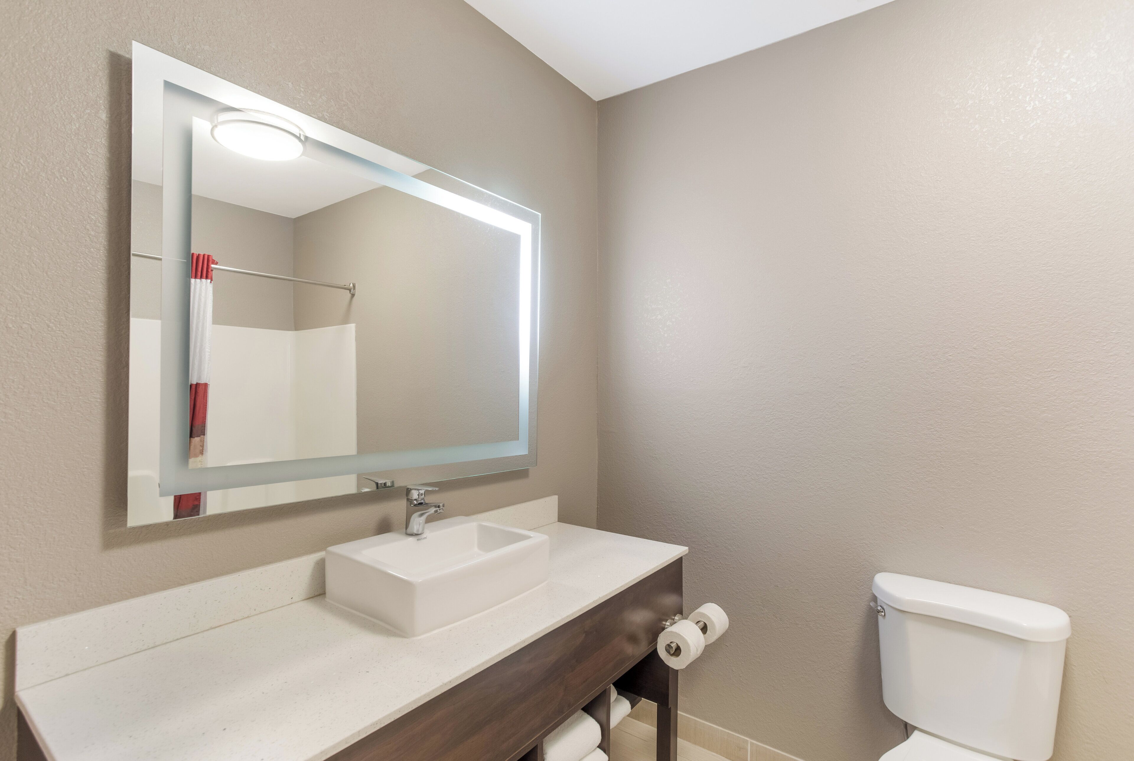 Un baño con un lavabo blanco, un espejo y un inodoro.
