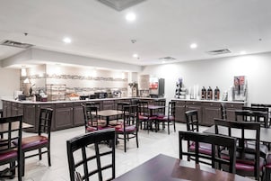 Un restaurante moderno con una barra central, varias mesas y sillas para comer.