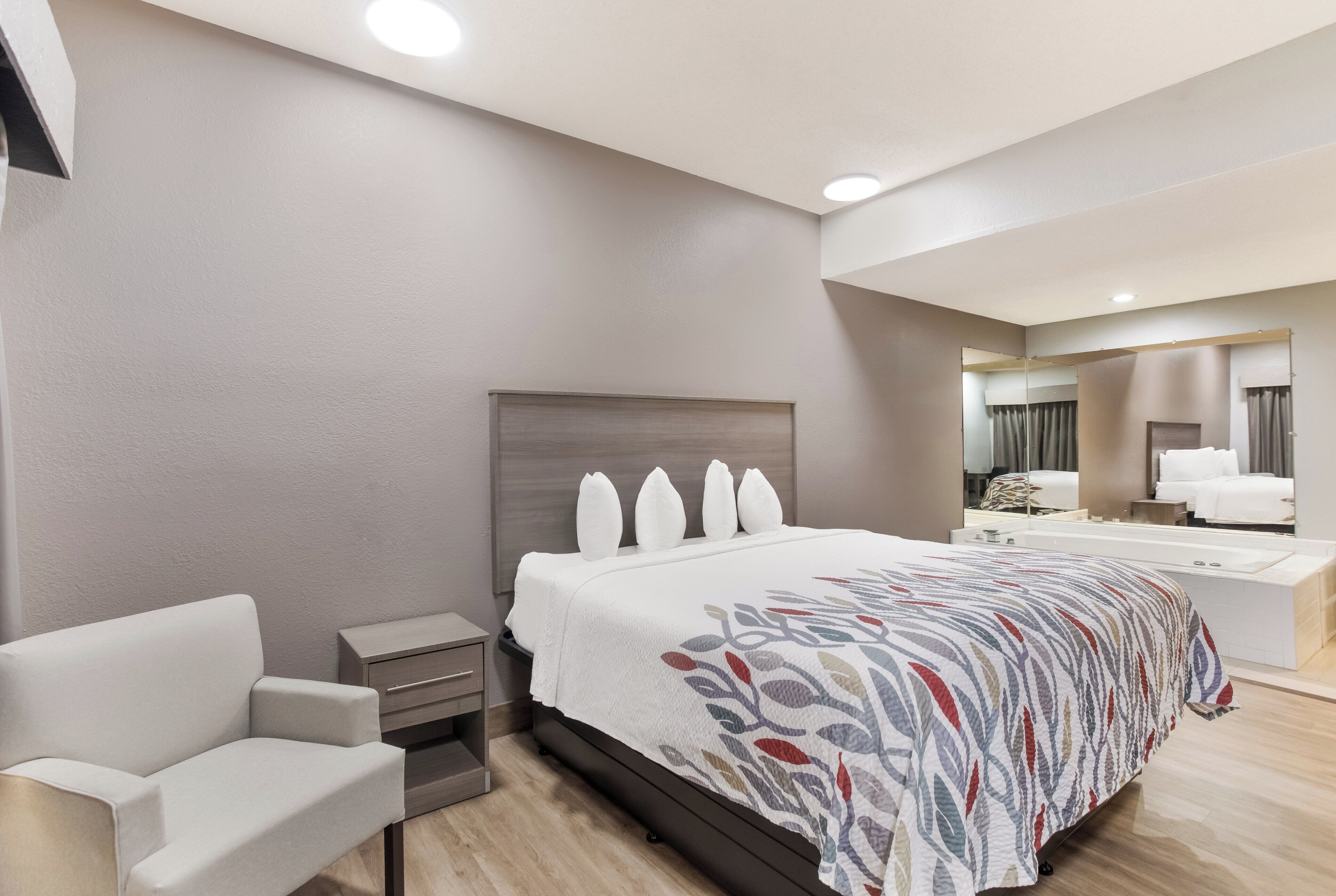 A modern hotel room with a large bed, a seating area, a vanity, and a bathroom.