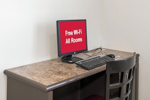 Escritorio de computadora con un monitor que muestra 'Wi-Fi gratis en todas las habitaciones' y un teclado.