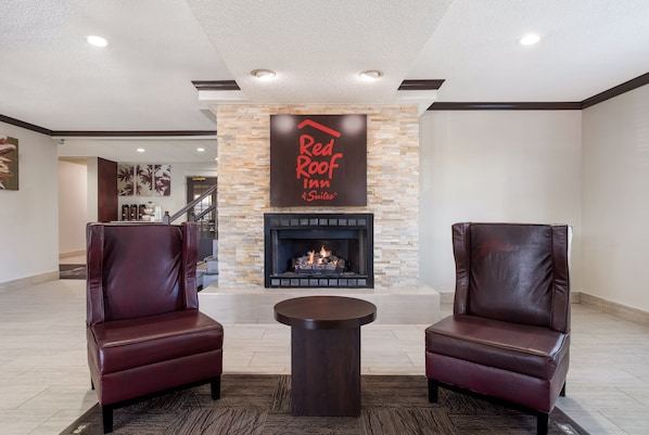 Vestíbulo de Red Roof Inn con chimenea de piedra, sillones de cuero y una mesita.