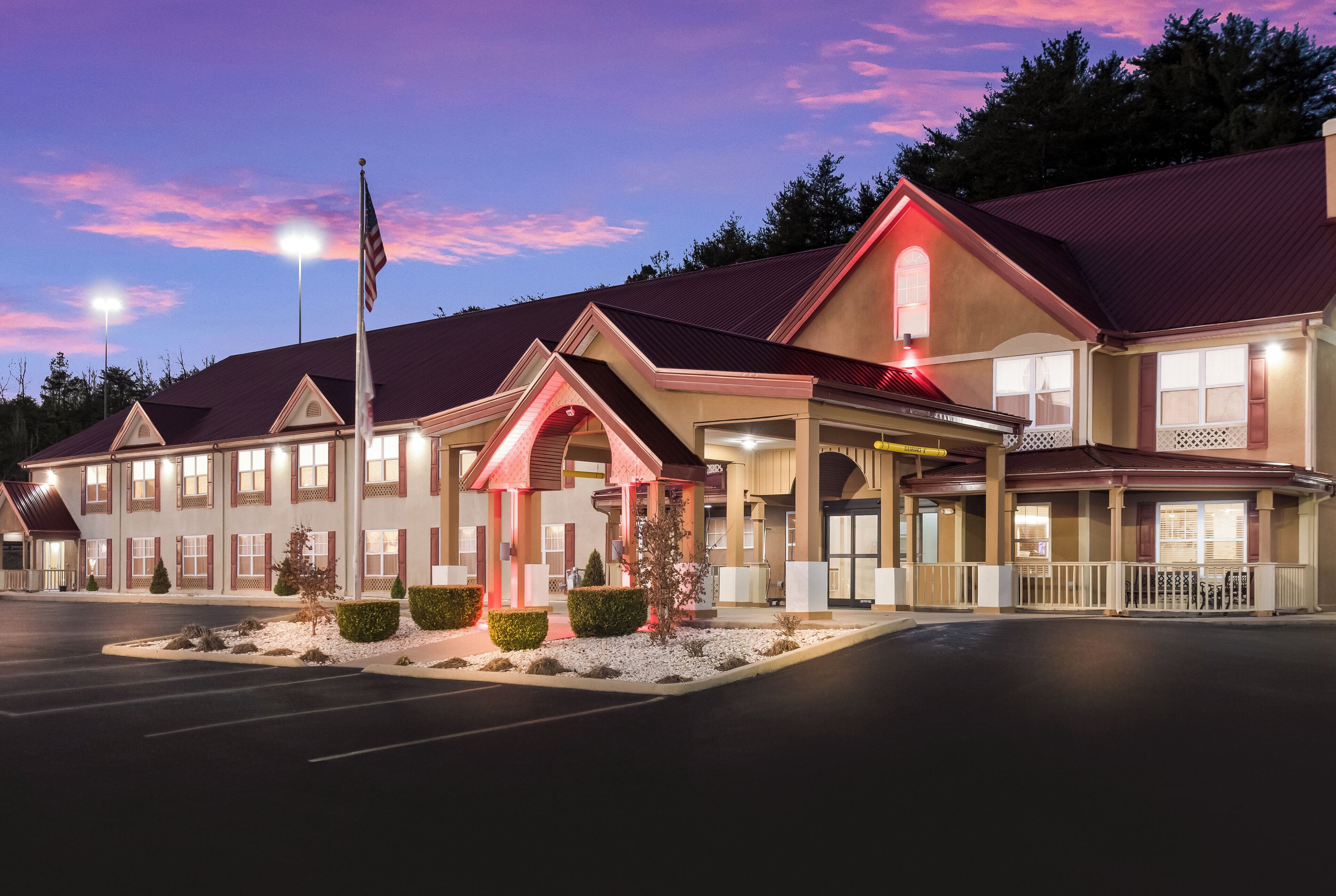 A hotel with a red roof, multiple windows, and a flagpole.