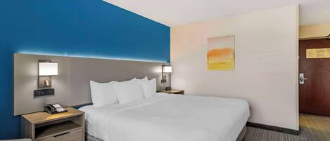 A hotel room with a large bed, bedside tables with lamps, a desk, and a chair.
