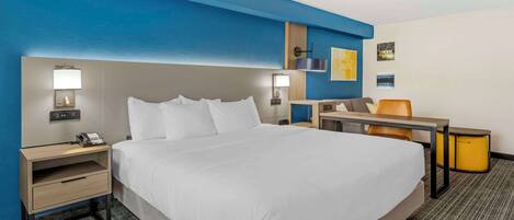 Una habitación de hotel con una cama grande, mesitas de noche, un escritorio y una silla.