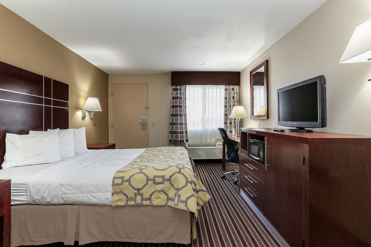 Une chambre d’hôtel avec un grand lit, un bureau avec une chaise, une télévision et une armoire.