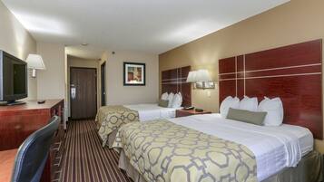 Habitación de hotel con dos camas, un escritorio con televisor y una puerta que da a otra habitación.