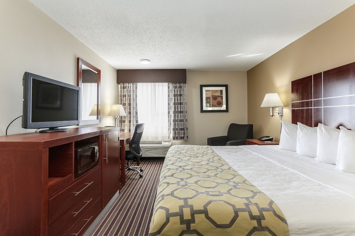 Une chambre d’hôtel avec un grand lit, un bureau avec une chaise, une télévision et deux lampes.