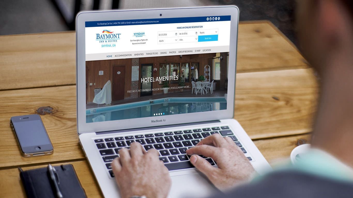 Una computadora portátil mostrando un sitio web de hotel con servicios como piscinas interiores y opciones para mascotas.