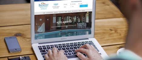 A laptop displaying a hotel website with amenities like indoor swimming pools and pet-friendly options.