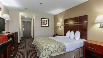 A hotel room with a bed, bedside tables, a desk with a TV, and a framed picture on the wall.