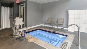 Zona de piscina con piscina azul, elevador para piscina accesible en silla de ruedas y dos sillas.