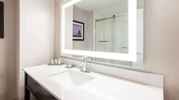 Un baño con un lavamanos blanco, un espejo grande y un cuadro en la pared.