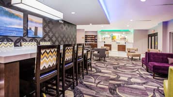A hotel lobby with a bar area, seating, and a view of the restaurant.