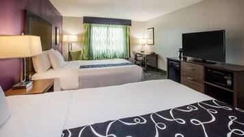 A hotel room with two beds, a desk with a chair, a television, and a microwave.