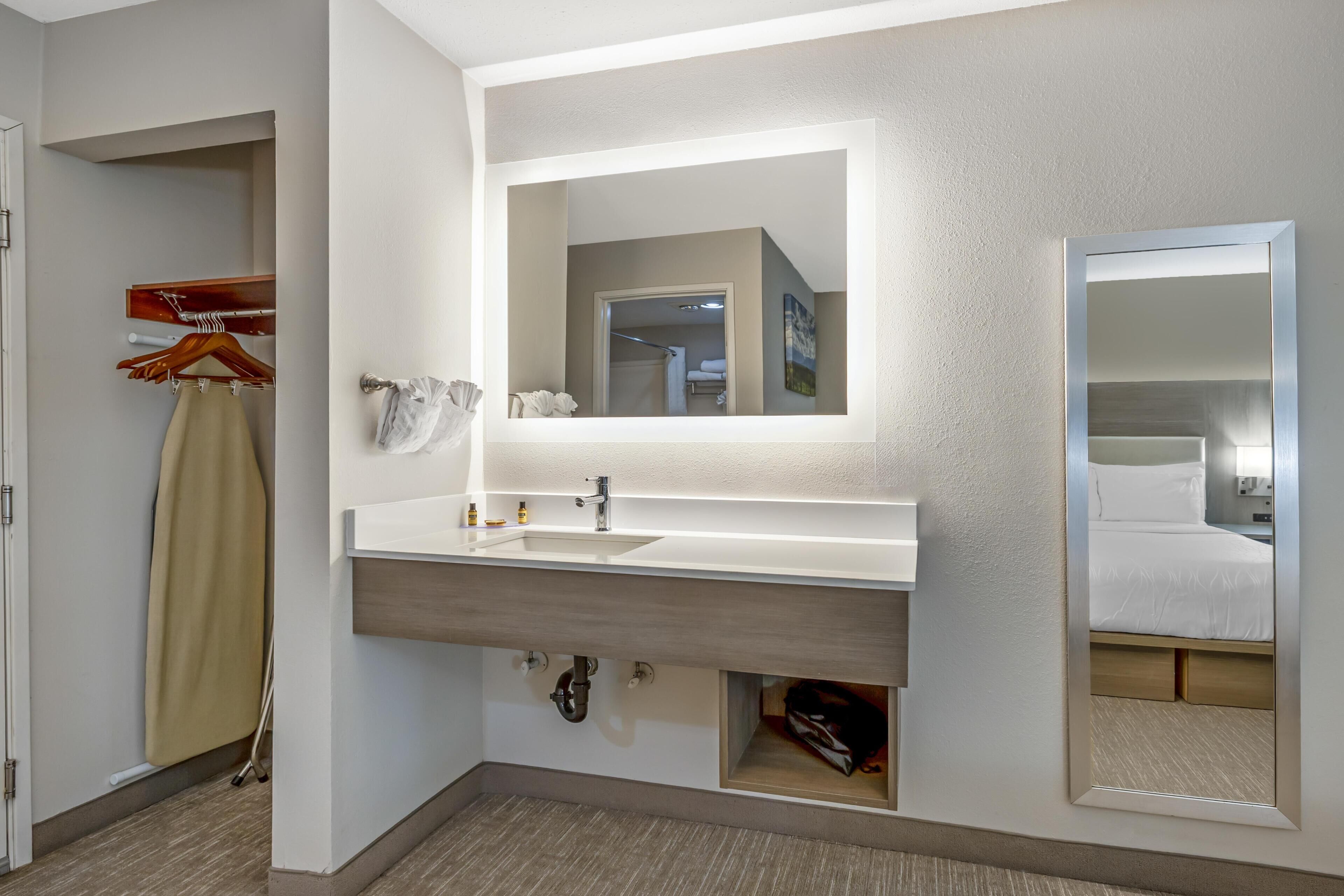 Un baño de hotel con un espejo grande, un lavabo y un perchero para toallas.