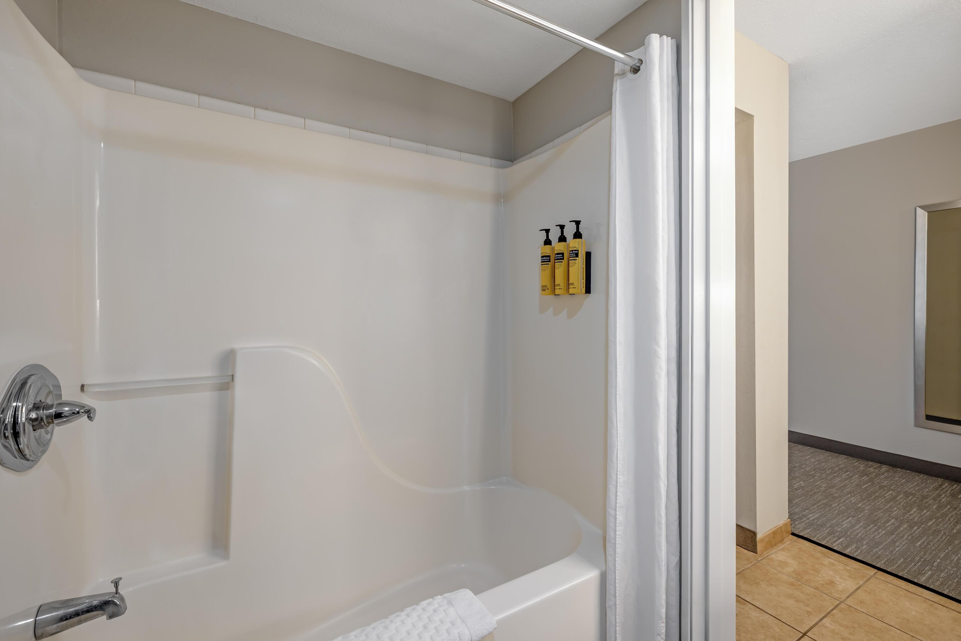A modern bathroom with a glass-enclosed shower, a white bathtub, and a towel rack.