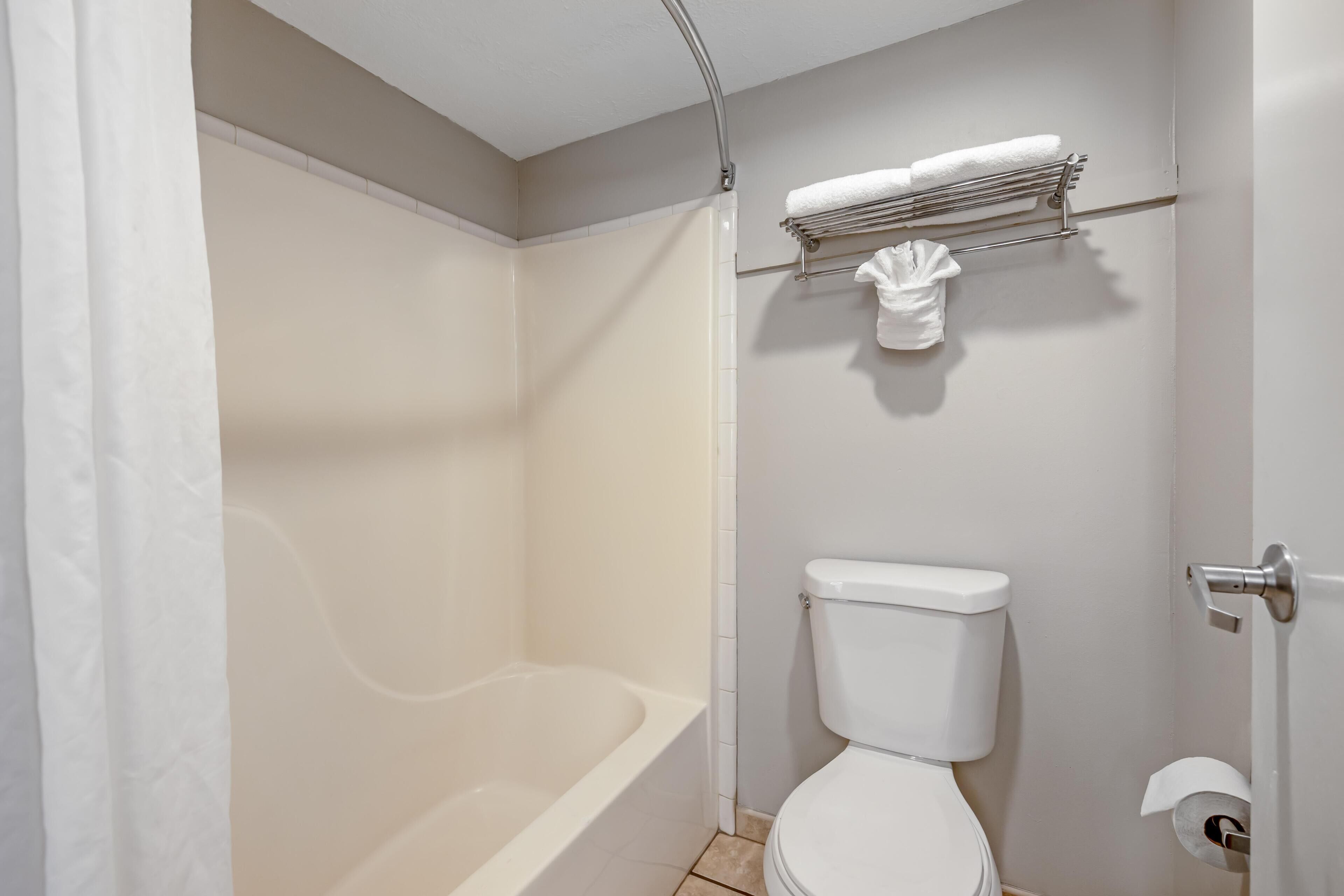 A bathroom with a bathtub, toilet, towel rack, and shower curtain.
