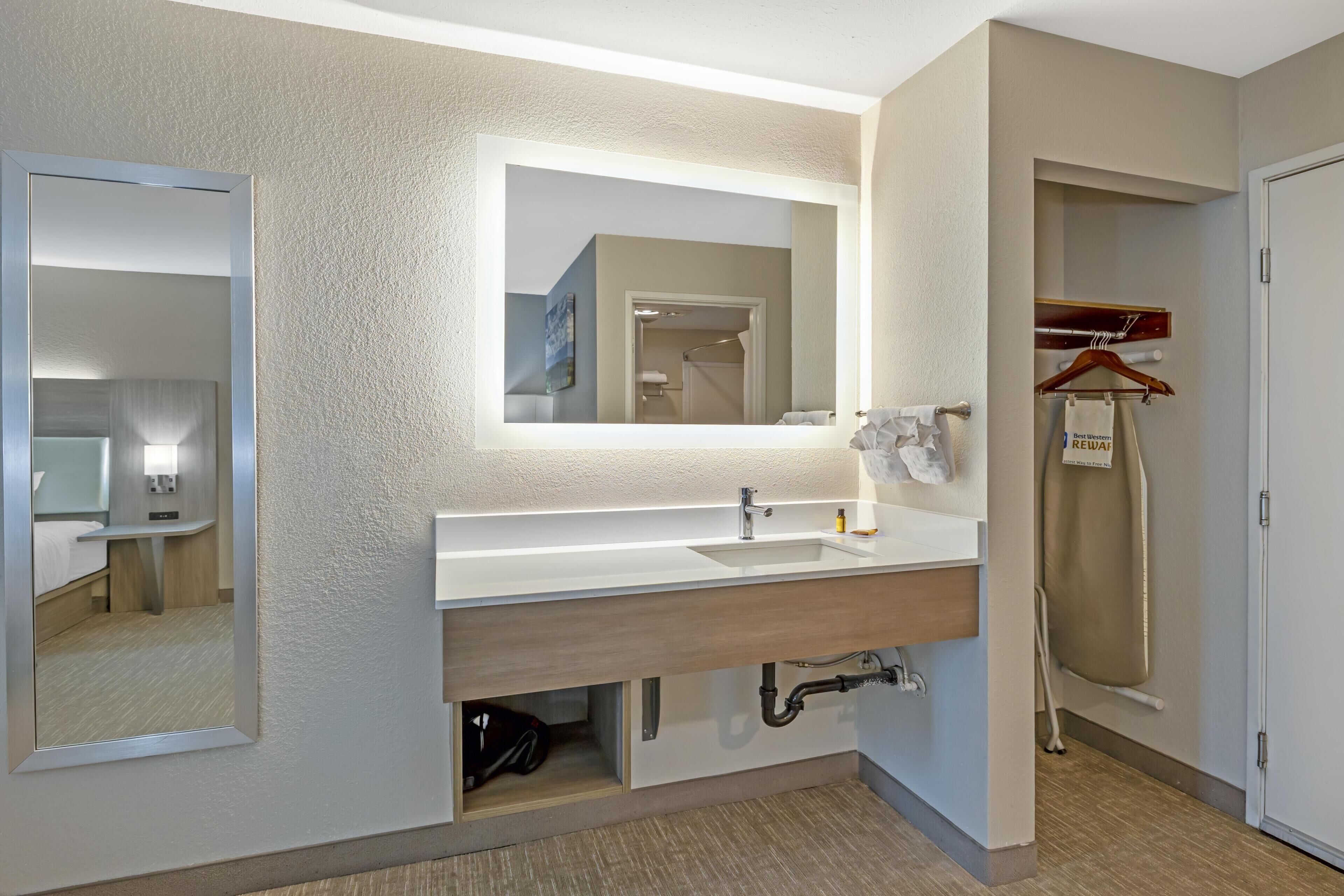 A modern bathroom with a large mirror, a sink, and a towel rack.