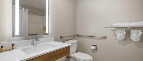 A bathroom with a white sink, mirror, and toilet.