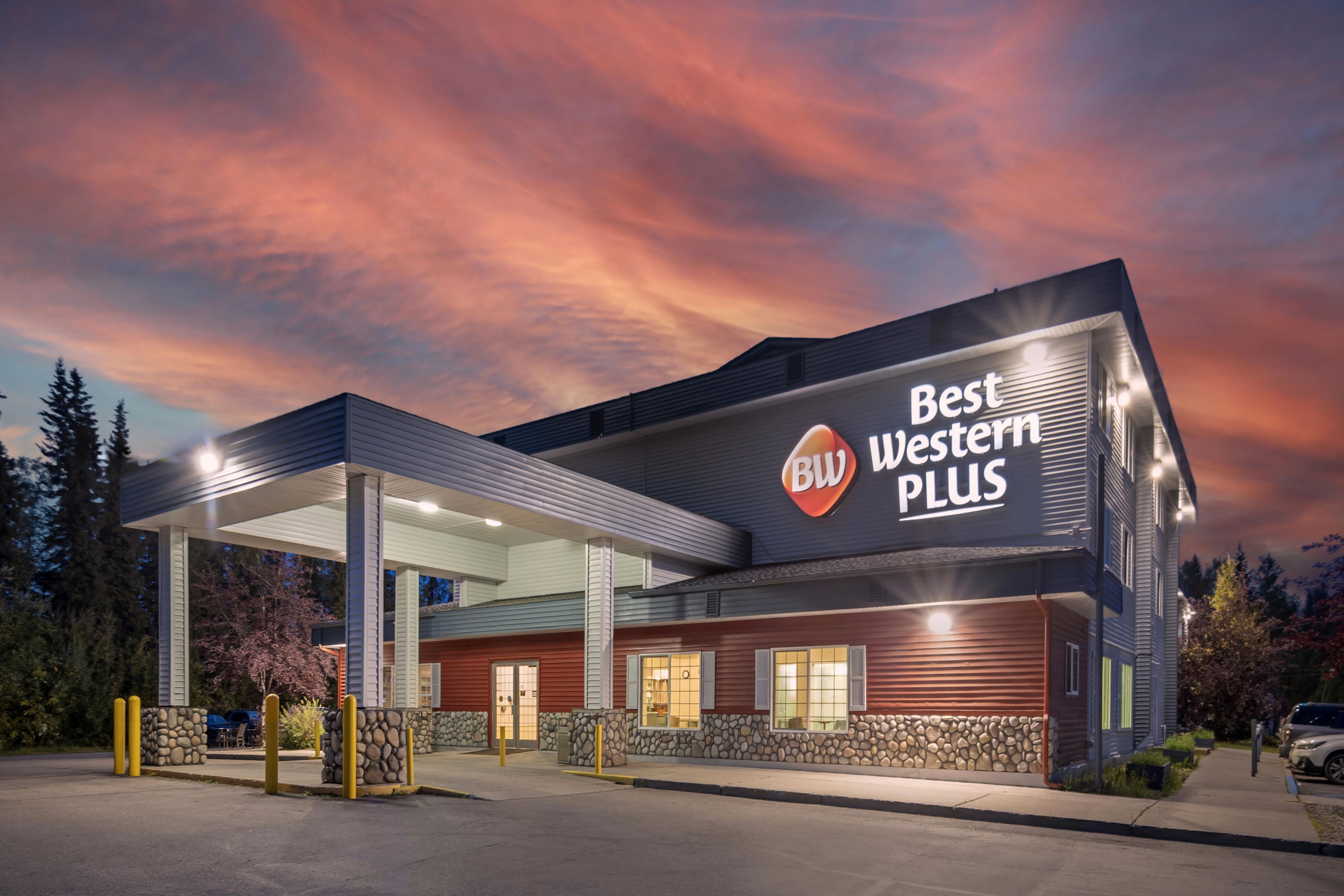 Een Best Western Plus hotel met een modern design, herkenbaar aan een opvallend bord en een overdekte parkeerplaats.
