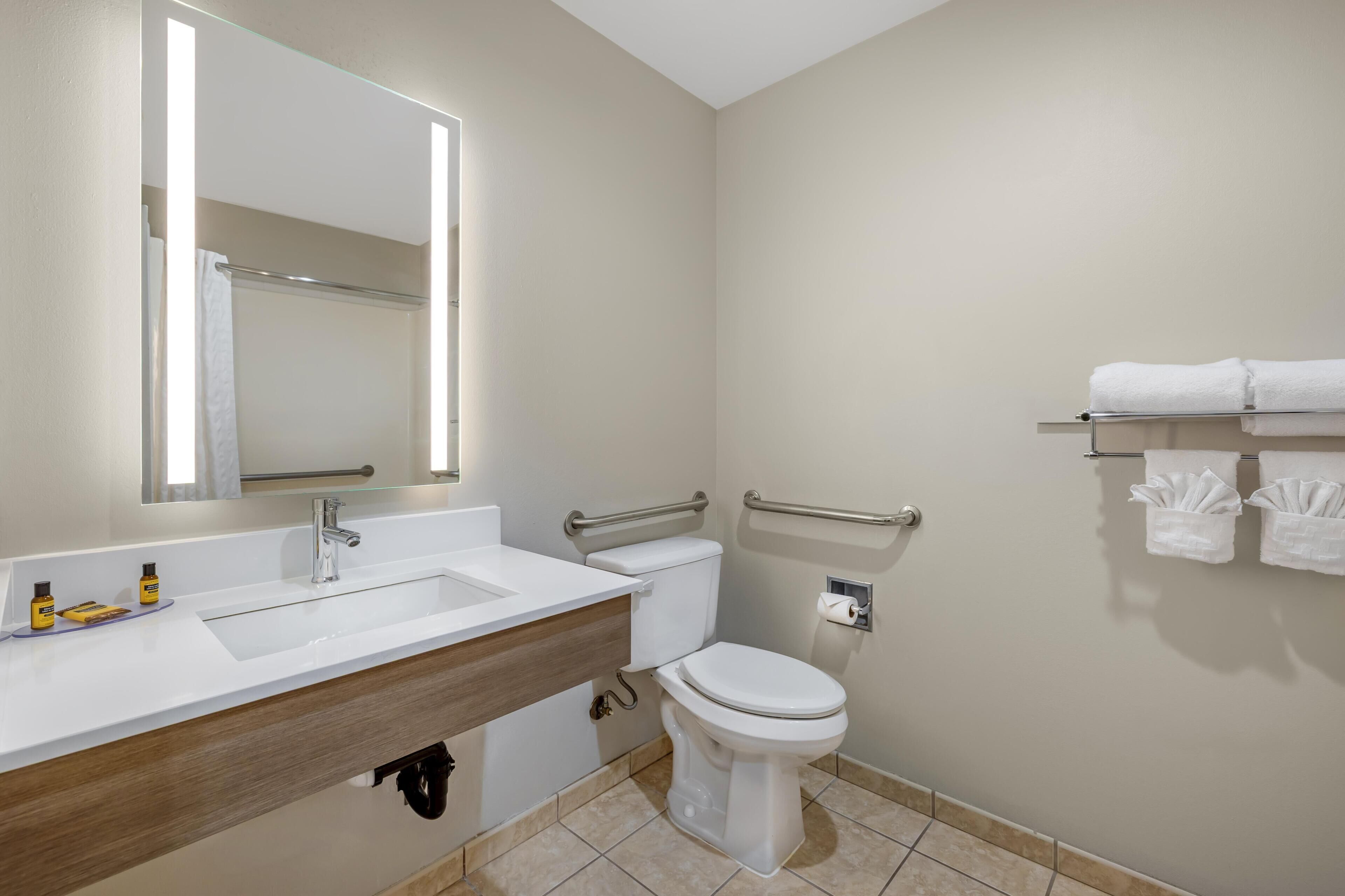 A bathroom with a white sink, mirror, toilet, and towel rack.