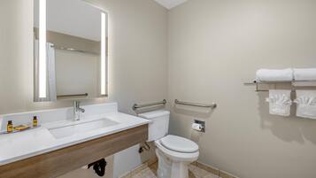Un baño con lavamanos blanco, espejo, inodoro y toallero.